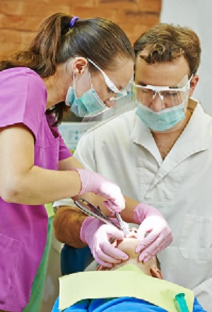 child dentist treat boy teeth under sedation with dental curing ultraviolet light equipment
